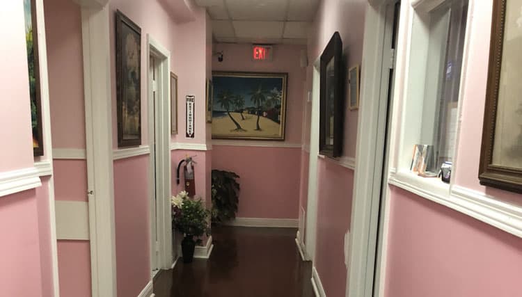 A hallway inside the clinic, with pink walls and framed pictures
